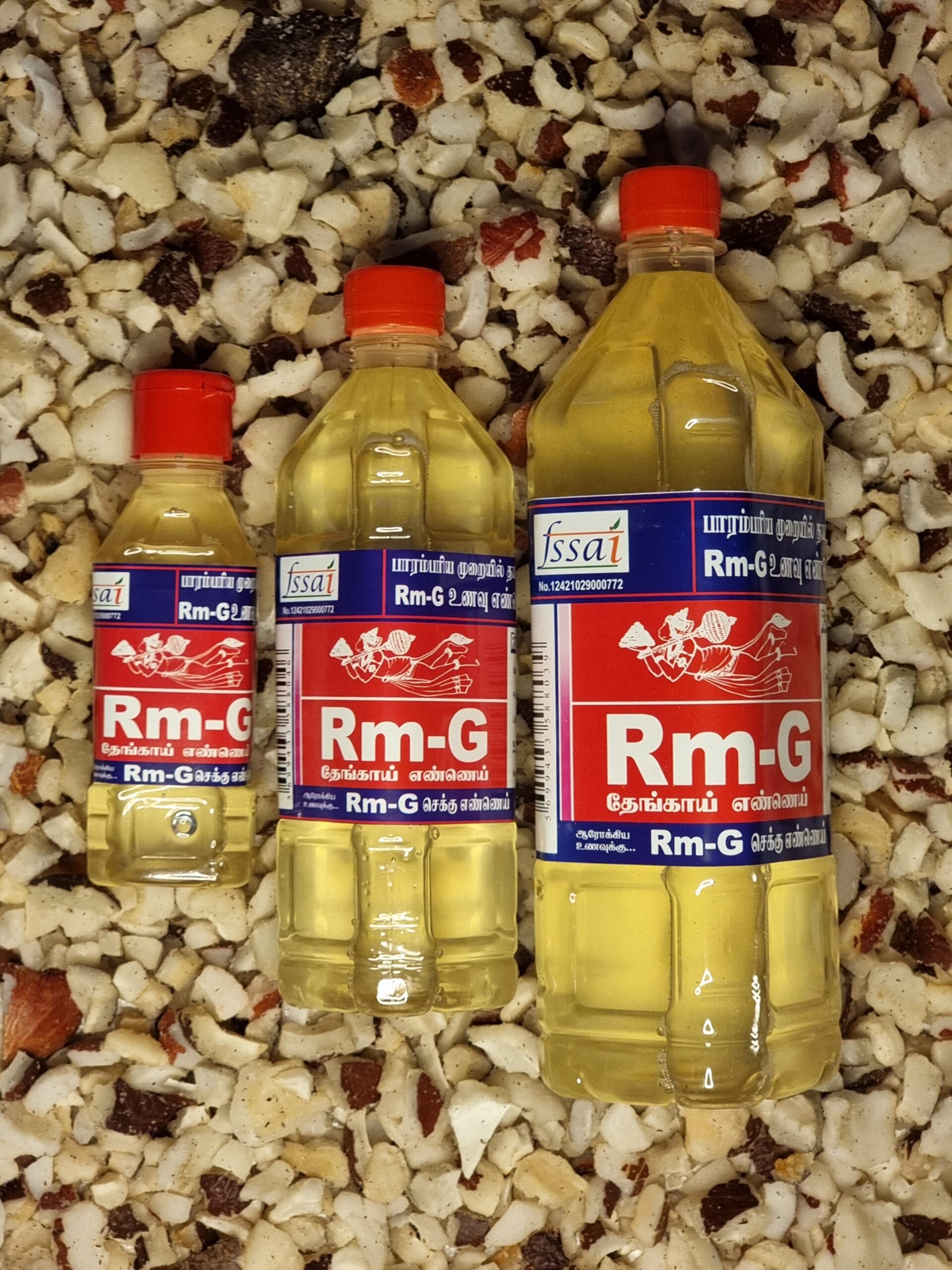 Unrefined Coconut Chekku Oil | Chekku Oil Three bottles of Rm-G Coconut Chekku Oil placed on dried coconut pieces.
